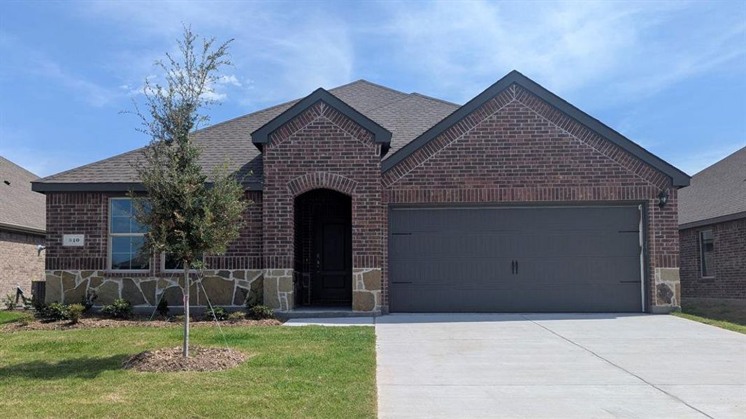 French country inspired facade featuring brick siding, a garage, driveway, and a shingled roof French country inspired facade featuring brick siding, a garage, driveway, and a shingled roof