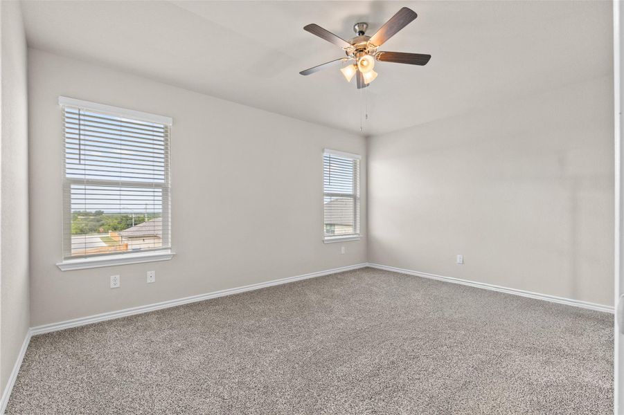Carpeted spare room with ceiling fan and baseboards