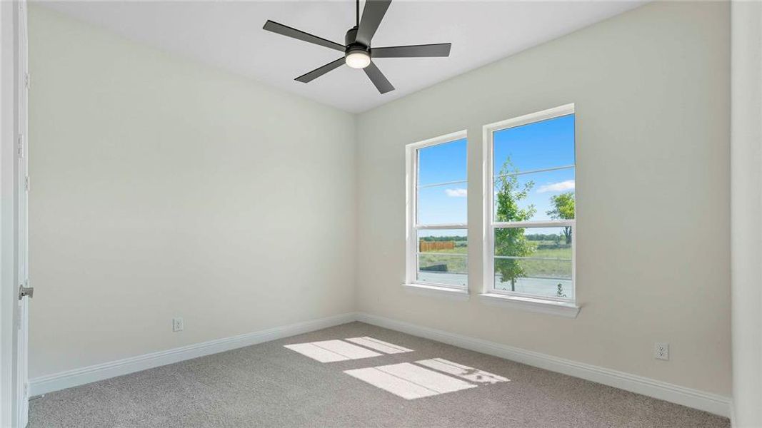 Bright room featuring two large windows, a ceiling fan with integrated lighting, and neutral carpet flooring