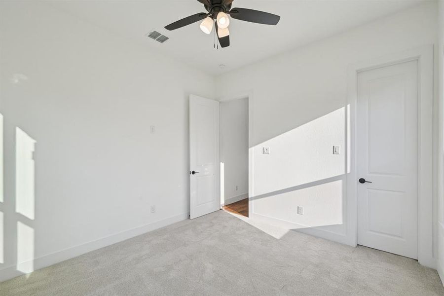 Unfurnished bedroom with light colored carpet and ceiling fan