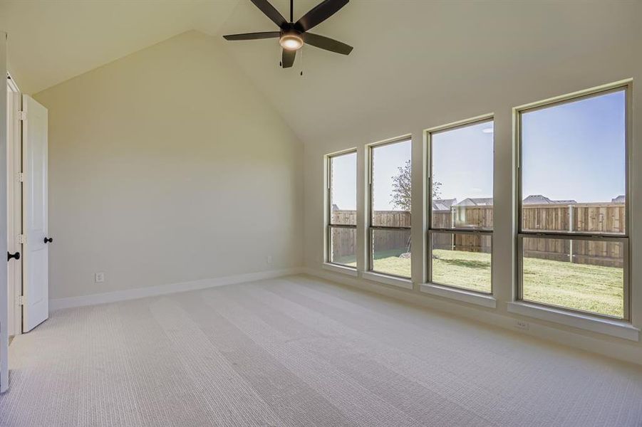 Spare room featuring light carpet, high vaulted ceiling, and ceiling fan