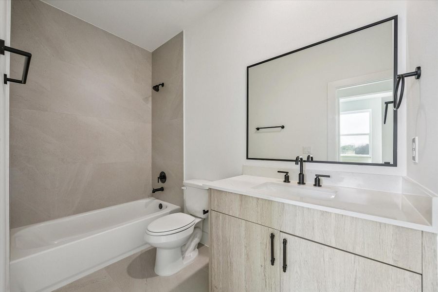 Stylish bath with framed mirror, tile detail, and modern vanity Stylish bath with framed mirror, tile detail, and modern vanity