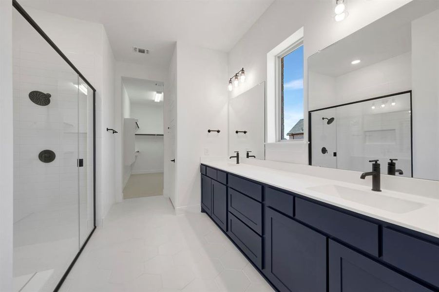Bathroom featuring double vanity, a shower stall, and light tile patterned flooring