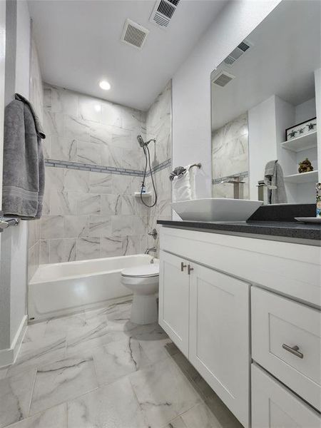 Full bathroom with tiled shower / bath, vanity, and toilet