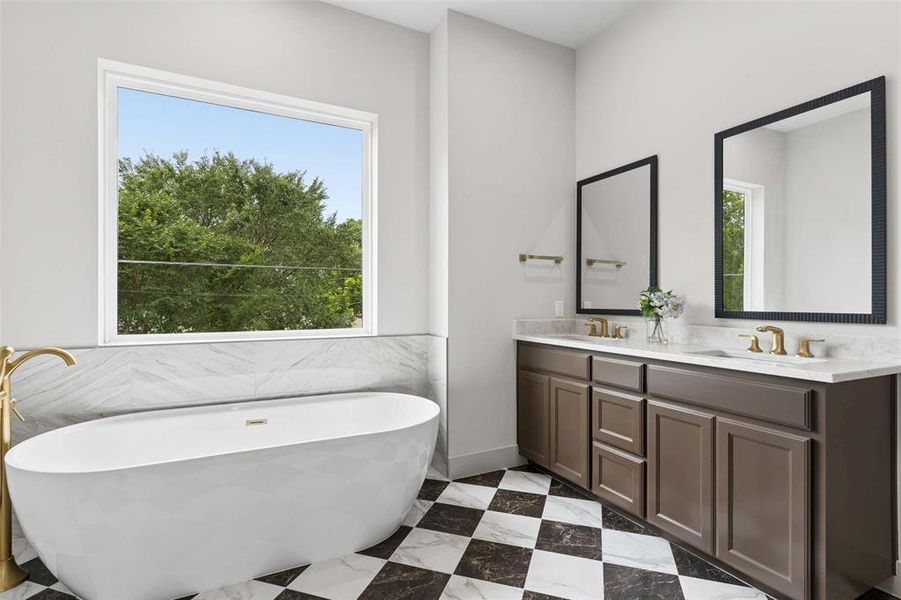 Luxurious bathroom featuring a freestanding soaking tub with a gold-finish floor-mounted filler, a double vanity with brown cabinetry and light-toned countertops, and a striking checkered floor. Luxurious bathroom featuring a freestanding soaking tub with a gold-finish floor-mounted filler, a double vanity with brown cabinetry and light-toned countertops, and a striking checkered floor.