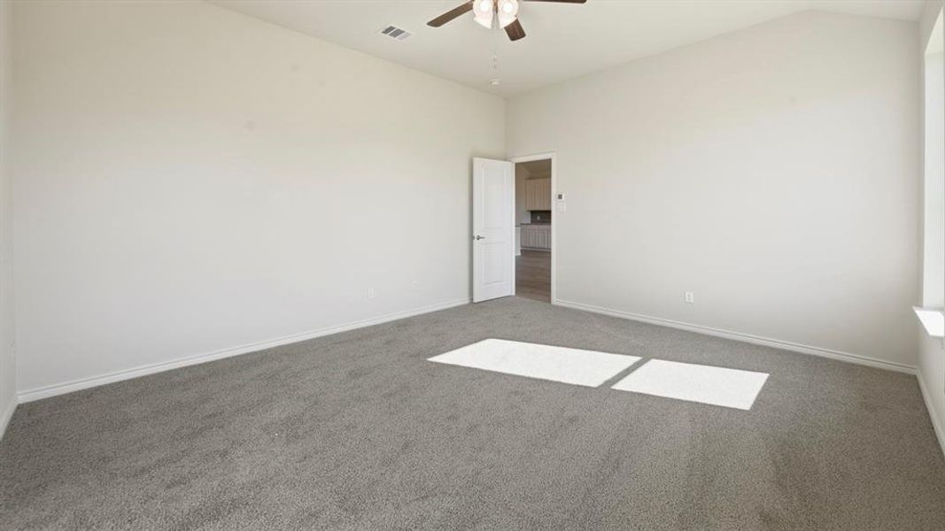Carpeted spare room with a ceiling fan and lofted ceiling