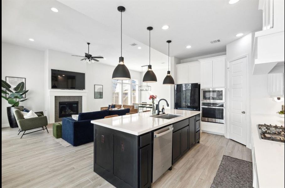 Kitchen with pendant lighting, stainless steel appliances, white cabinetry, light wood-type flooring, and recessed lighting