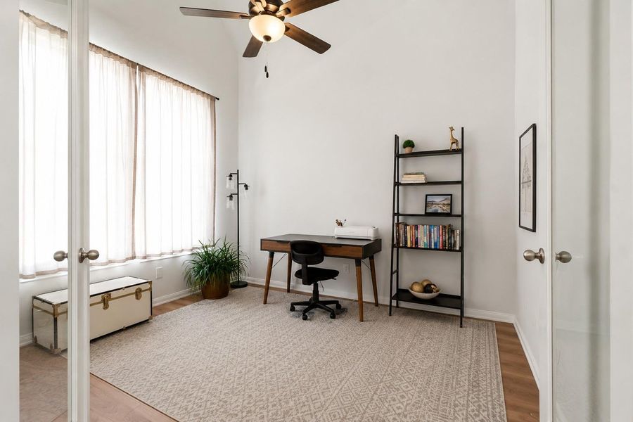 Bright home office with large windows and a ceiling fan.