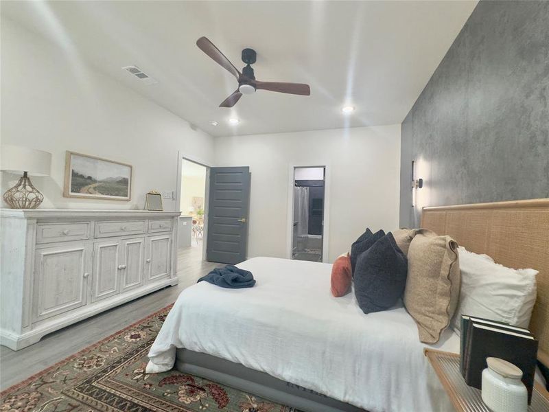 Bedroom with ensuite bath, ceiling fan, and hardwood / wood-style flooring