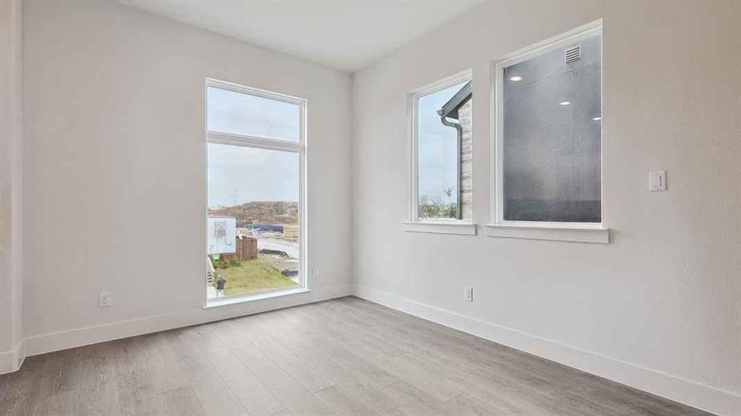 Room featuring light gray wood-finish flooring, white baseboards, and white walls