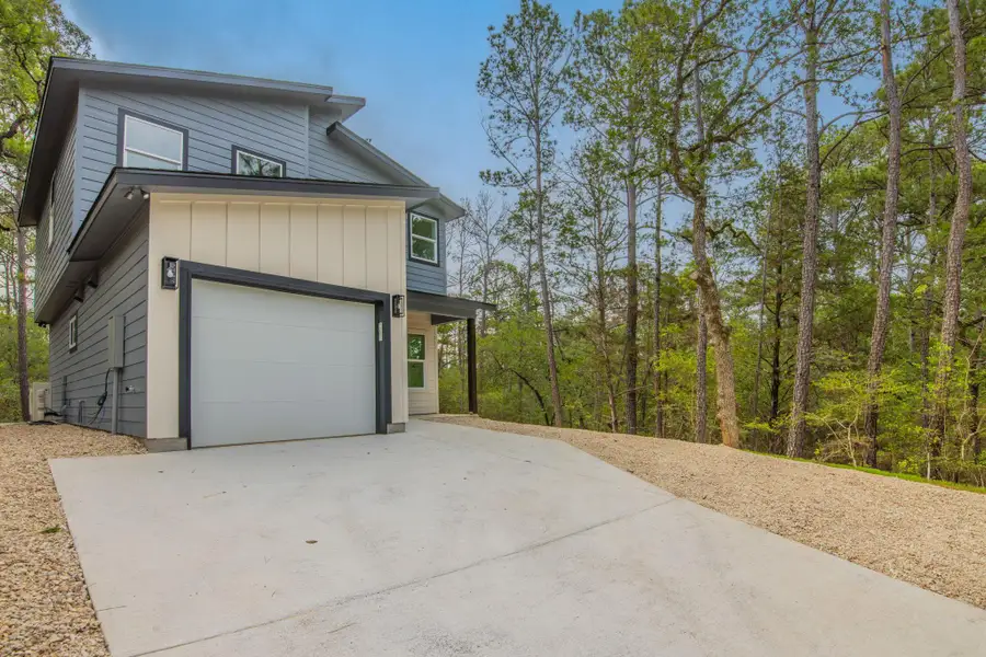 Contemporary two-story exterior featuring a two-tone facade, attached garage, concrete driveway, and natural landscaping with mature trees Contemporary two-story exterior featuring a two-tone facade, attached garage, concrete driveway, and natural landscaping with mature trees