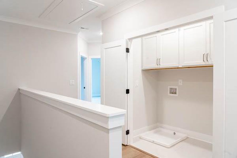 Clothes washing area featuring cabinets, light wood-type flooring, crown molding, and washer hookup Clothes washing area featuring cabinets, light wood-type flooring, crown molding, and washer hookup