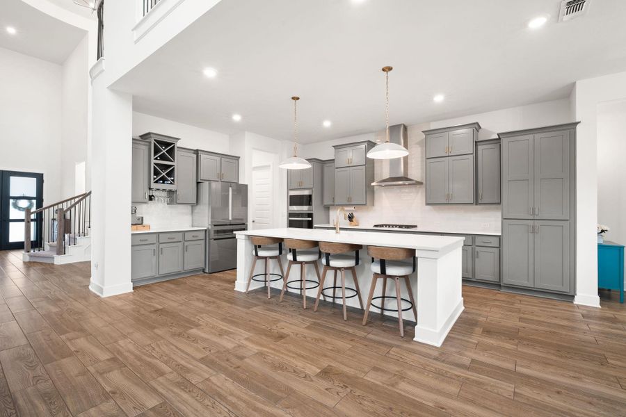 A sleek, open-concept kitchen with high ceilings and rich hardwood flooring flows seamlessly into the main living area.