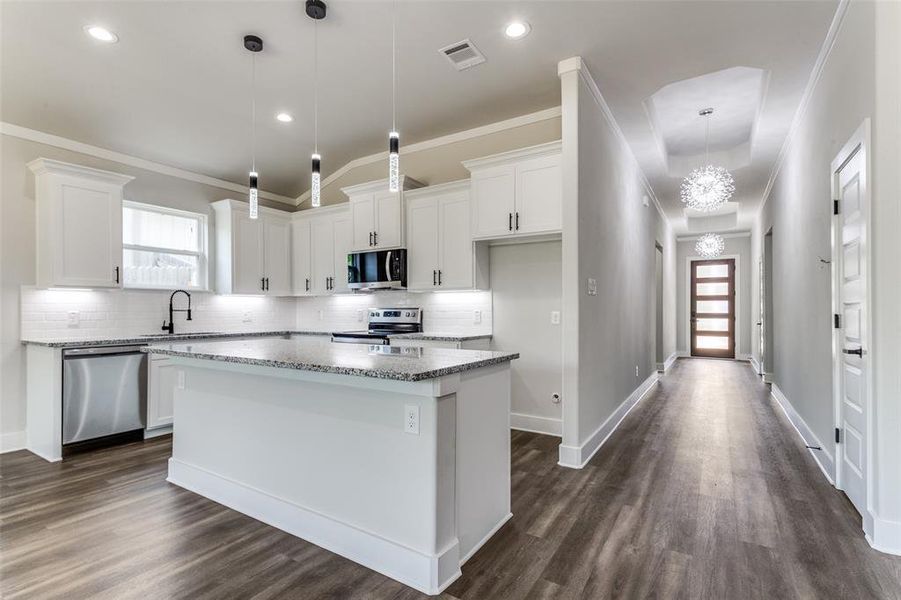 Kitchen featuring stainless steel appliances, dark hardwood / wood-style flooring, a center island, and plenty of natural light