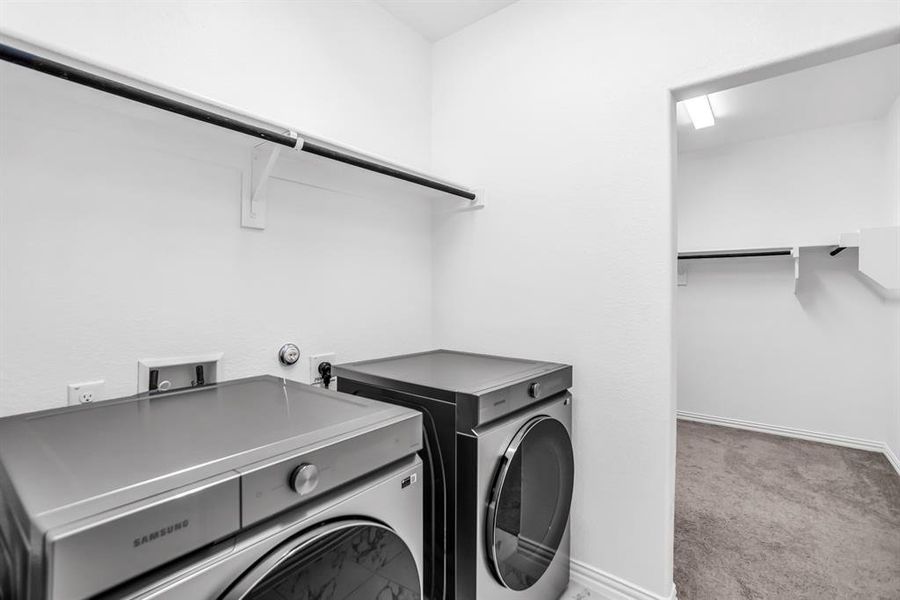 Laundry area featuring a hanging rod, shelving, and a nearby walk-in closet with additional shelving