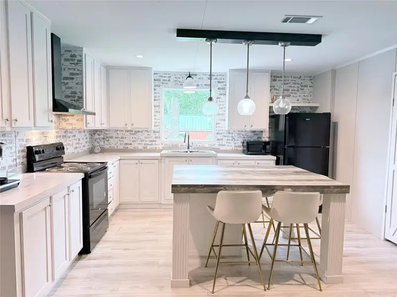 A clean, modern kitchen offers an island with pendant lighting and integrated seating.