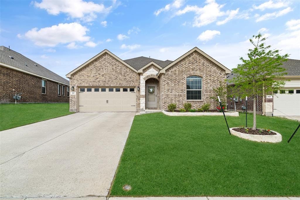The property features an attractive brick exterior with stone accents, a well-maintained lawn, and a concrete driveway leading to a two-car garage The property features an attractive brick exterior with stone accents, a well-maintained lawn, and a concrete driveway leading to a two-car garage