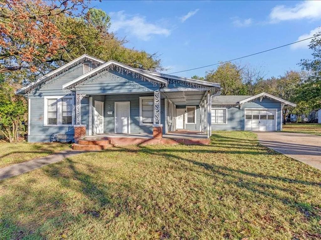 View of front of house with covered porch, a front yard, driveway, and a garage