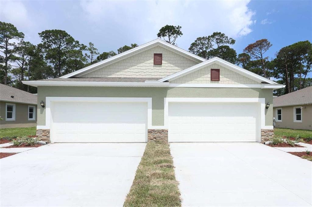Front exterior of a new home in Halifax Plantation Villas, Ormond Beach, FL, highlighting curb appeal (Image 1).