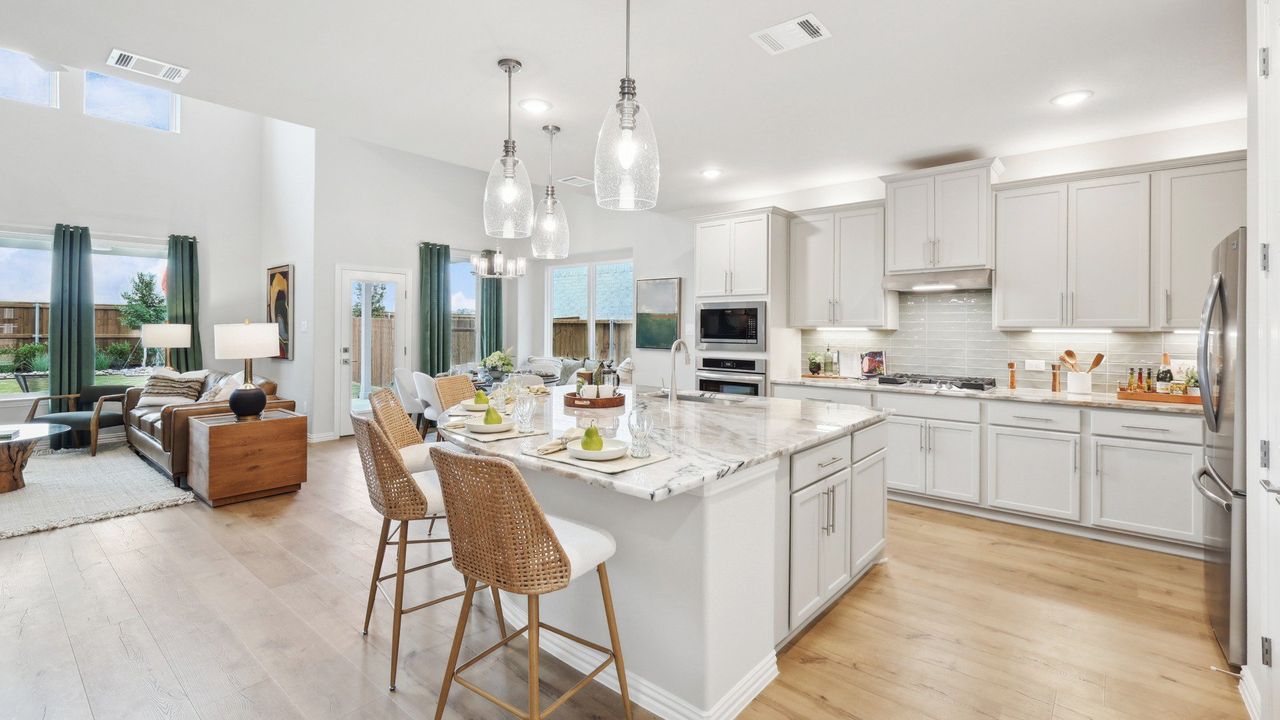Chic kitchen with grey cabinetry, marble countertops, and pendant lights in DRB Homes Magnolia plan