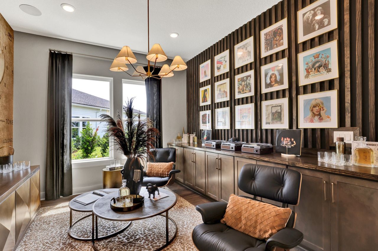 Music-themed lounge with framed vinyl album covers on dark accent wall, leather chairs, and built-in cabinets Music-themed lounge with framed vinyl album covers on dark accent wall, leather chairs, and built-in cabinets