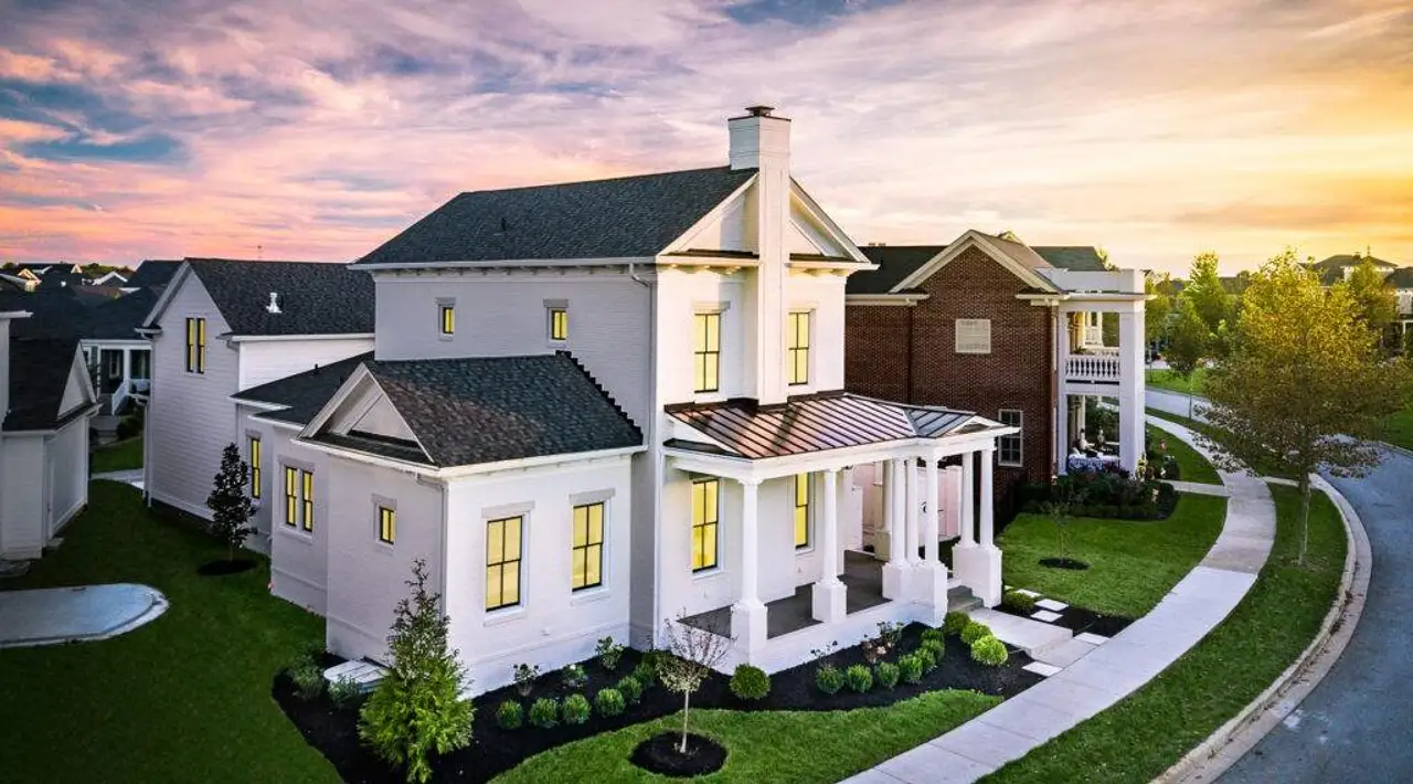 Front/Side of house at dusk with a porch, a chimney, a lawn, and a shingled roof. Please note these are pictures of home to be built. Photos are copyrighted by C3Studios, LLC.