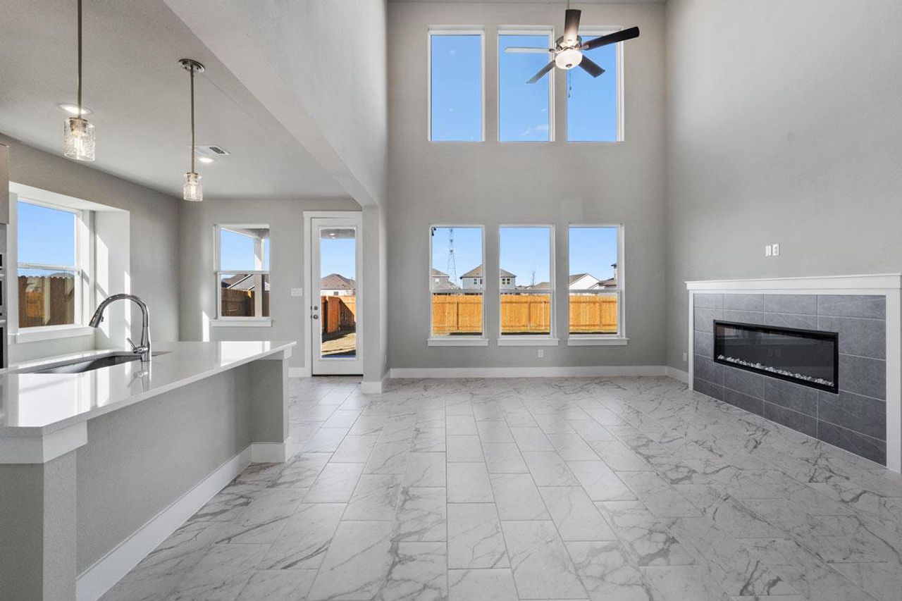 Double-height ceilings and a sleek modern fireplace define this open-concept living area.