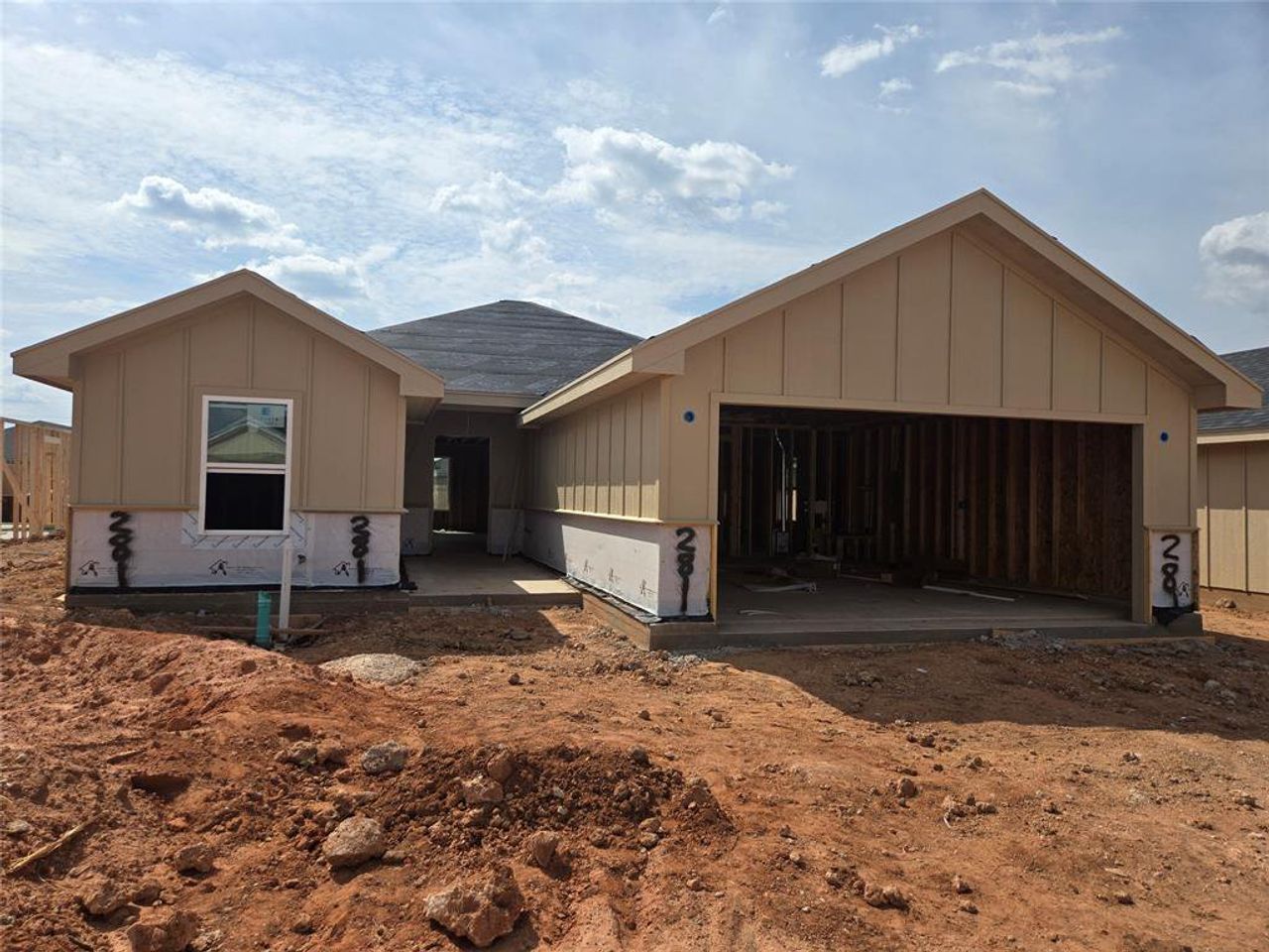 Property under construction with board and batten siding, a garage, and a patio area