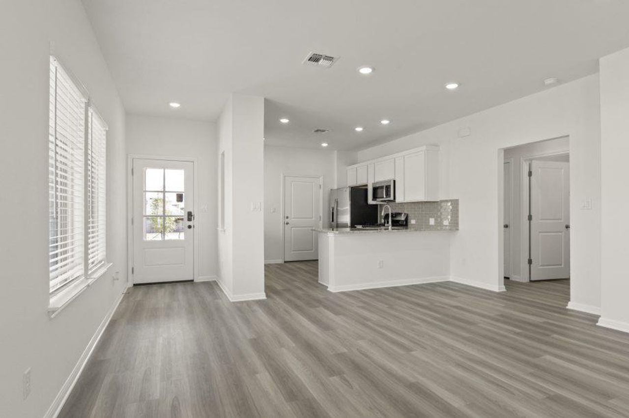 Kitchen featuring white cabinets, open floor plan, tasteful backsplash, recessed lighting, and wood finished floors