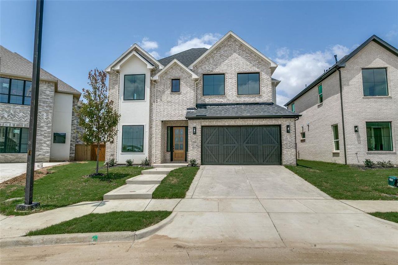 View of front of property featuring concrete driveway, brick siding, a garage, and roof with shingles