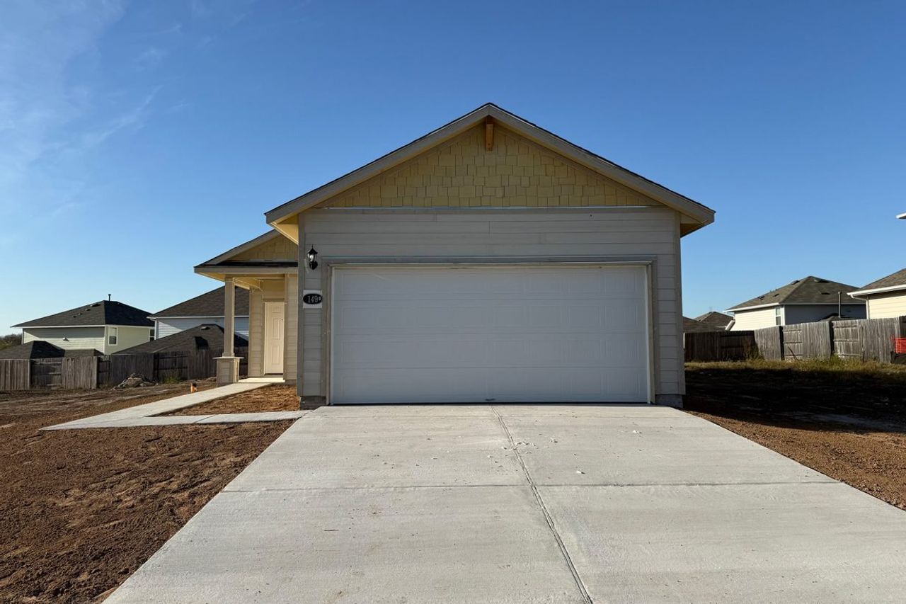 Image of the front of a construction home with yellow accents and a white garage door