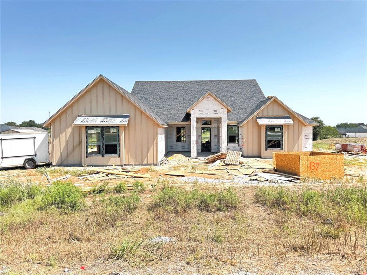 New construction residence featuring a grey shingle roof, board and batten siding, multiple gables, and dark-framed windows