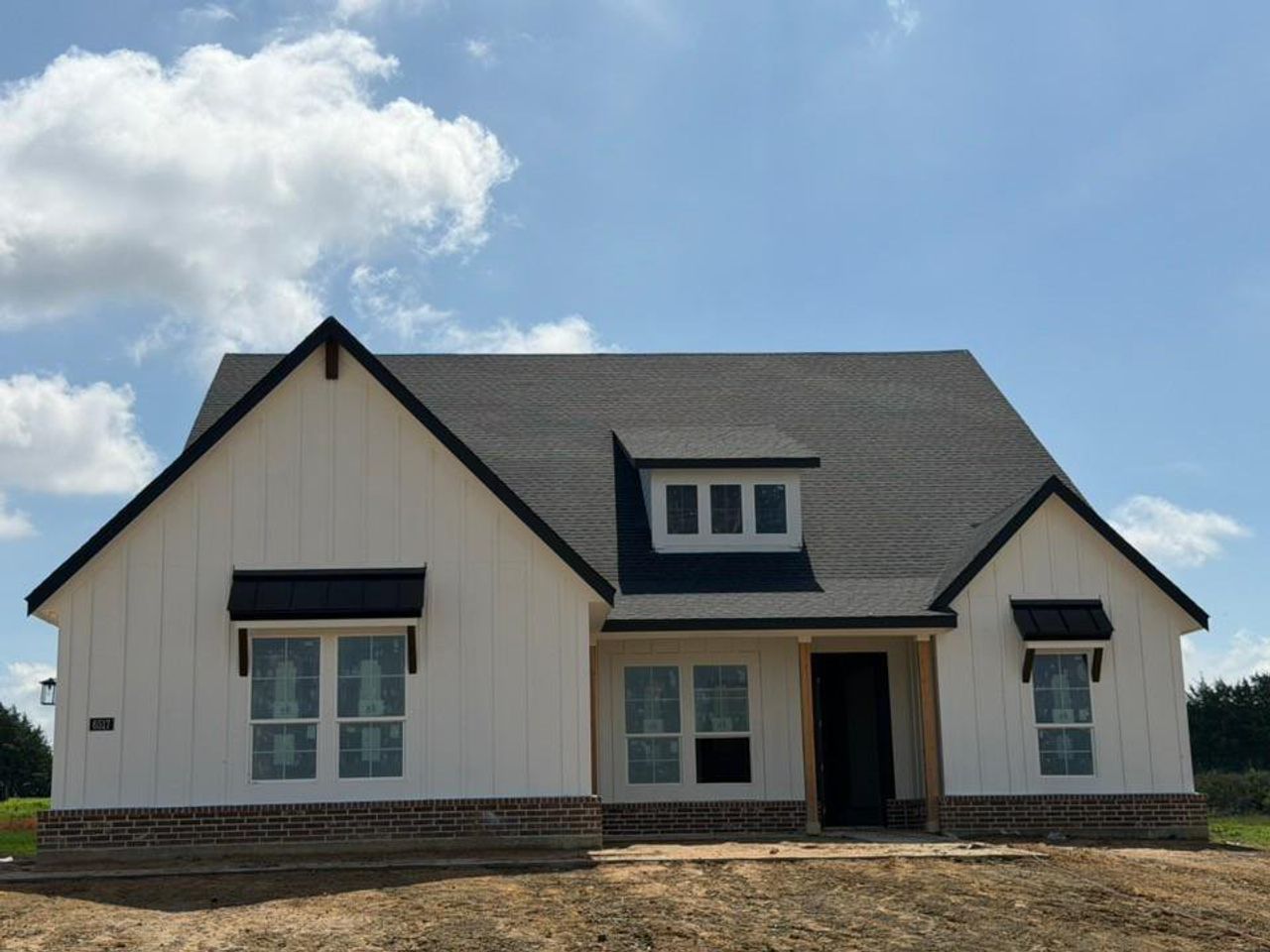 Modern farmhouse-style exterior featuring white vertical siding and a dark shingle roof