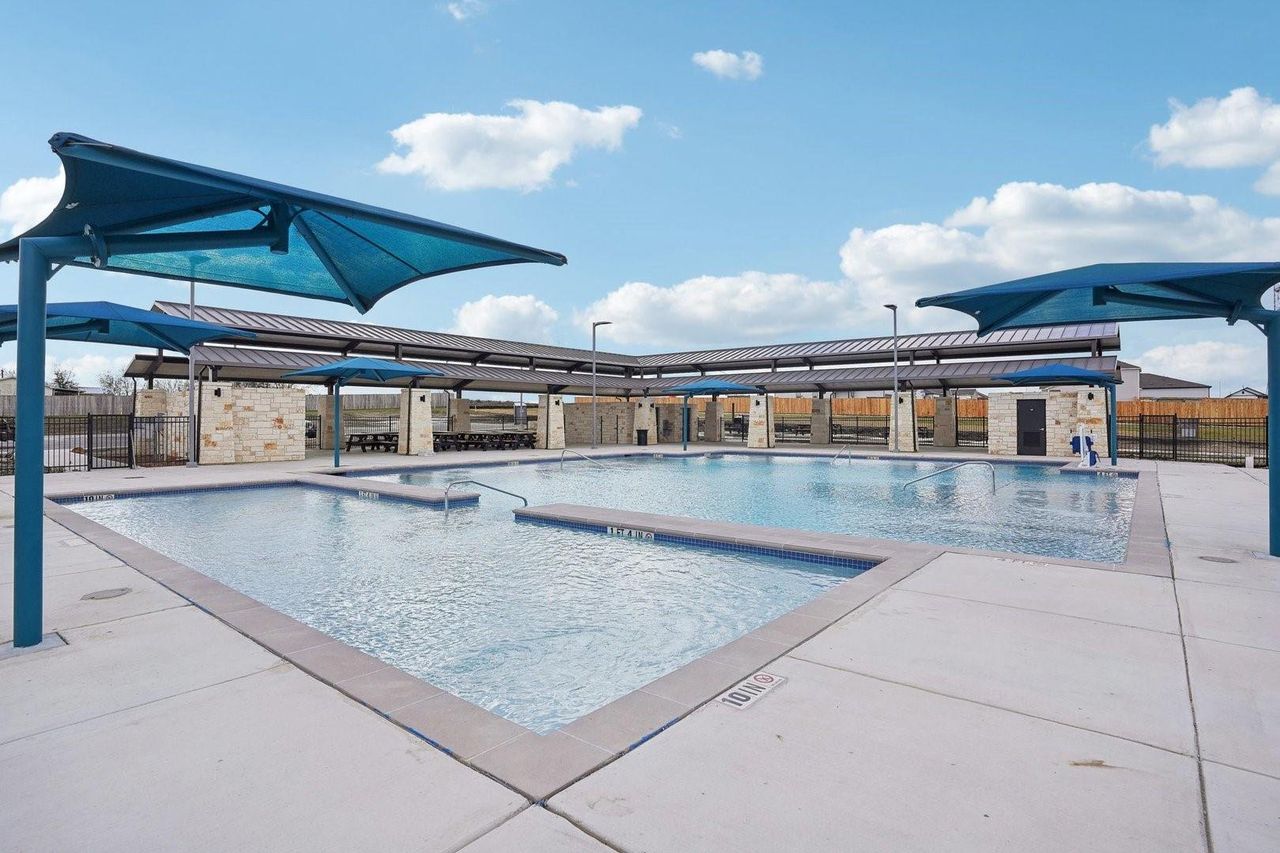 A refreshing community pool with covered seating areas offers endless summer enjoyment under open skies.