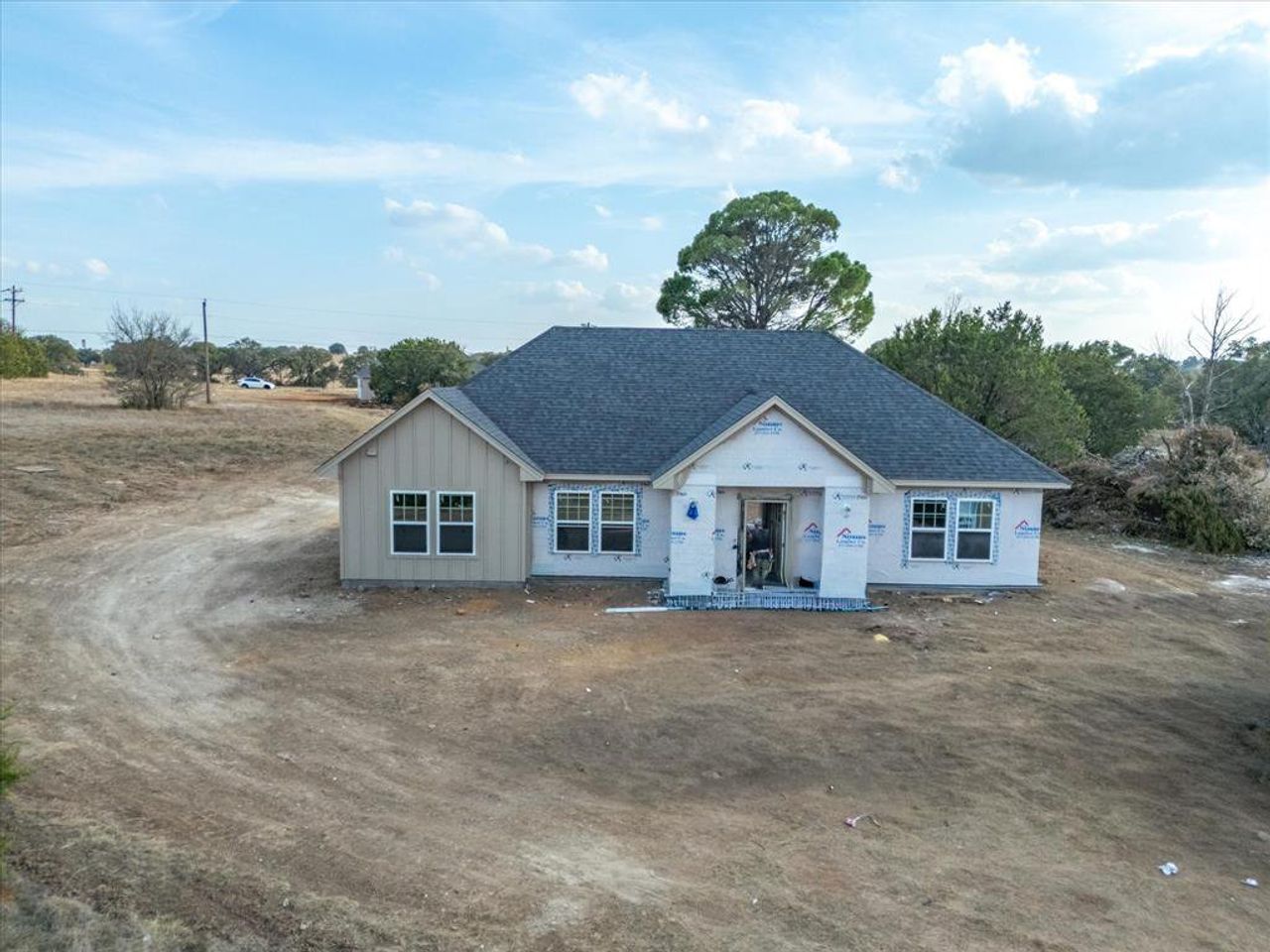 Property under construction with a shingled roof and board and batten siding