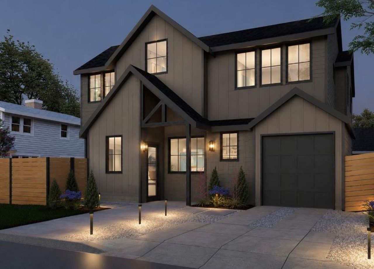 Illuminated by modern landscape lighting, this striking home features a contrasting dark roofline and an inviting entryway.