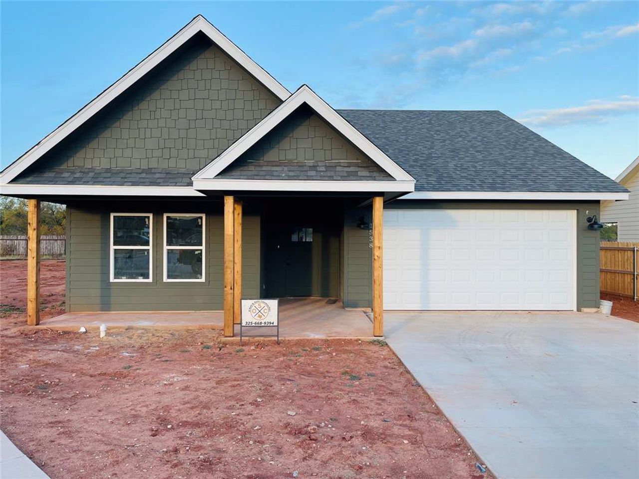 View of front facade featuring a shingled roof, a garage, driveway, and a porch