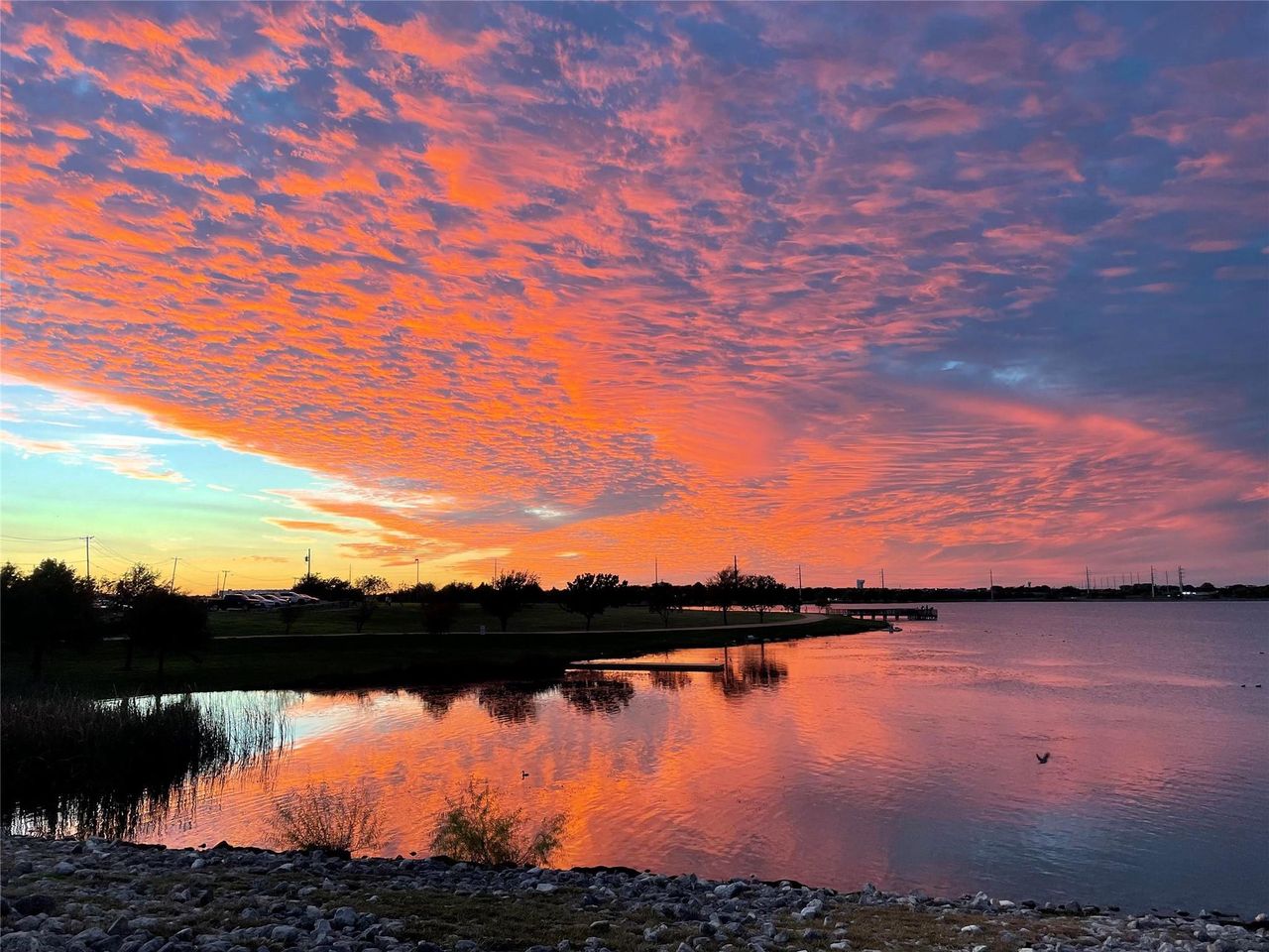 Vibrant sunset skies reflect beautifully over the peaceful neighborhood lake waters.