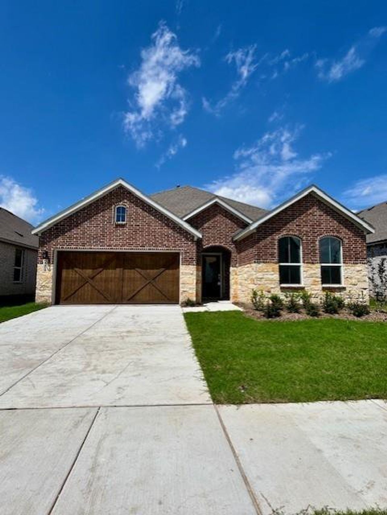 Brick and stone facade featuring a wood-finish garage door