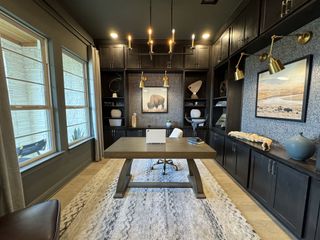 Model Home A sophisticated home office with dark cabinetry, stylish lighting, and large windows offering plenty of natural light.