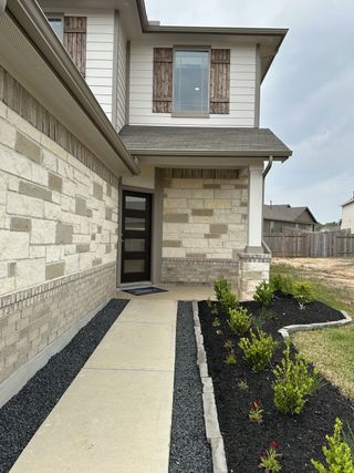 Charming stone and siding home with rustic shutters in Meadow Park by First America Homes (Conroe, TX).