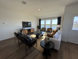 A cozy living room with wooden floors, a white sofa, modern TV unit, and large windows offering scenic views.