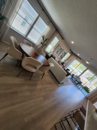 An elegant open-plan living area with wood flooring, cozy dining space, and ample natural light through large windows.