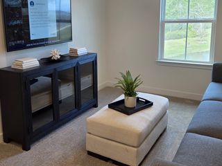 A cozy living area featuring a comfy sectional, elegant console, and natural light from a large window.