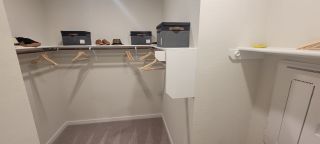 Model Home A spacious walk-in closet featuring shelving, hanging space, and sleek boxes for organized storage.
