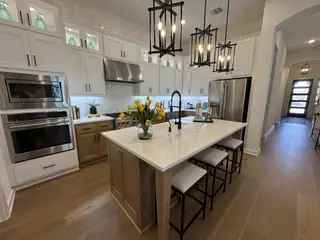 A spacious kitchen featuring a white and wood island, pendant lighting, and decorative glass cabinets.