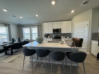Modern kitchen with sleek white cabinetry, a spacious island, and a stylish dining area featuring elegant gray tones.
