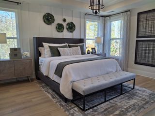 Model Home A cozy bedroom with a plush bed, modern side tables, and floor-to-ceiling windows. Neutral tones with elegant decor accents.