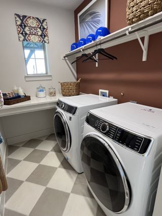 A stylish laundry room with modern appliances, checkered flooring, and warm-toned walls in Solterra by David Weekley Homes (Mesquite, TX).