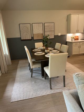 A chic dining area with a dark wood table, cream chairs, and modern art accents on the wall.